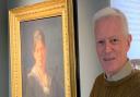 Cllr John Crockford-Hawley pictured beside a portrait of Ivy Millicent James held at Weston Museum.