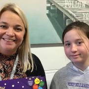 Jo Arnold is pictured holding chocolate selection boxes with a student.
