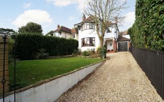 The impressive property has a large gravel driveway and lawn at the front